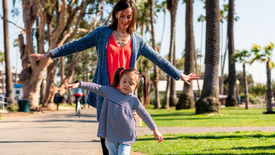A daugter leading her mum, balancing along a curb in Santa Monica, California.