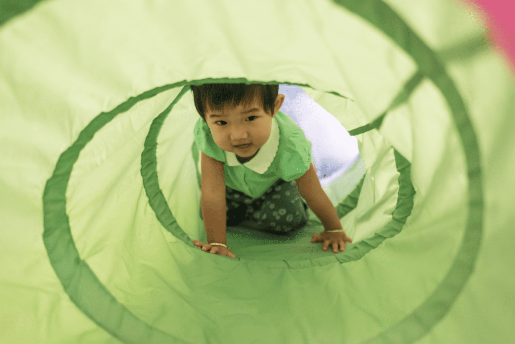 A baby crawls through a pop-up tunnel.