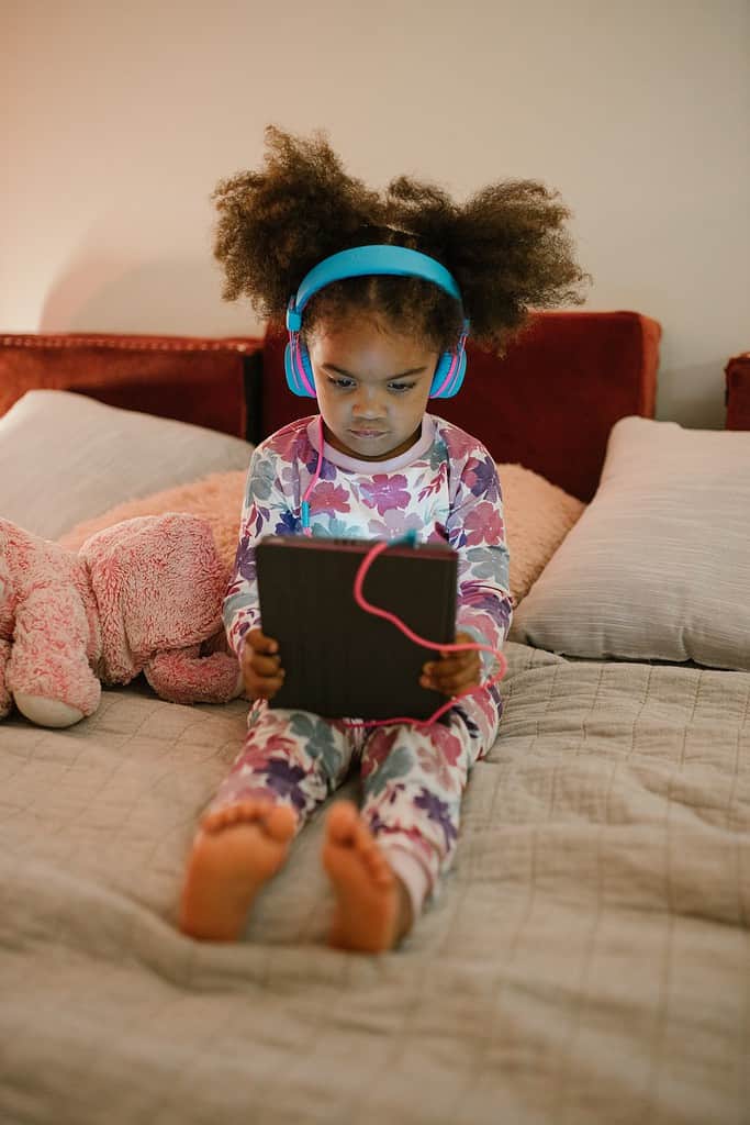 A child watches a tablet while wearing headphones.