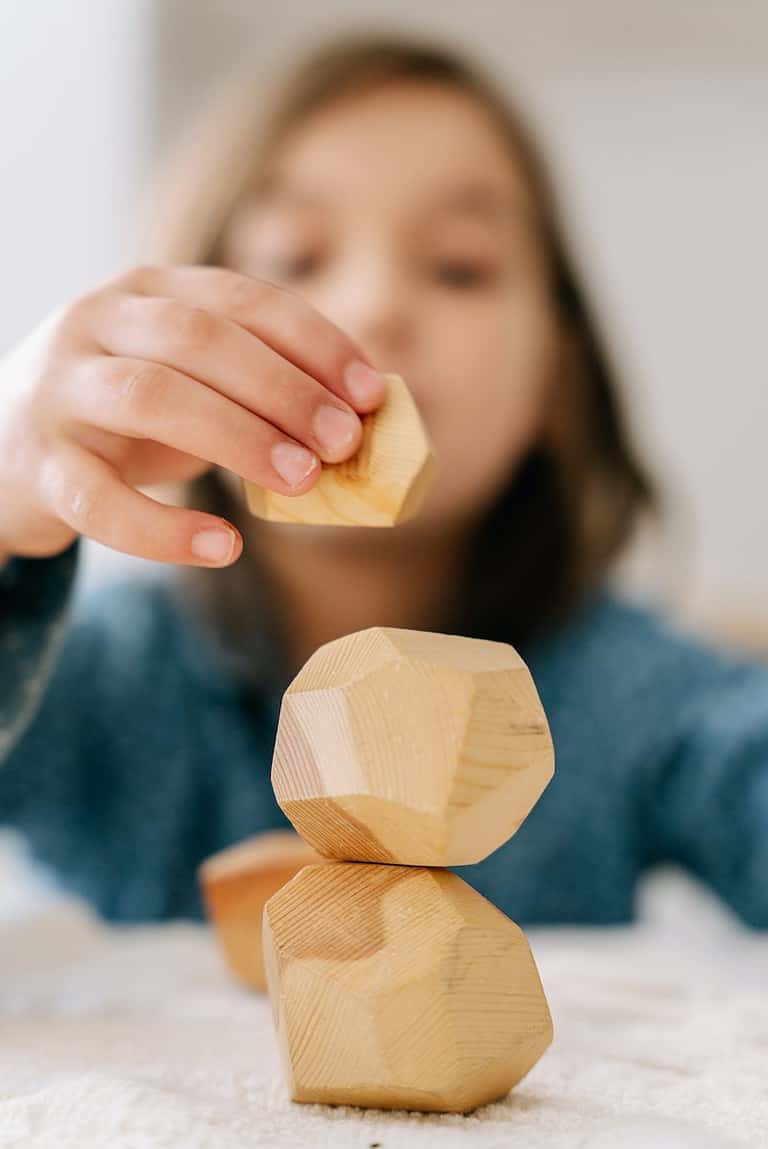 A child balances stacking blocks during a block activity.