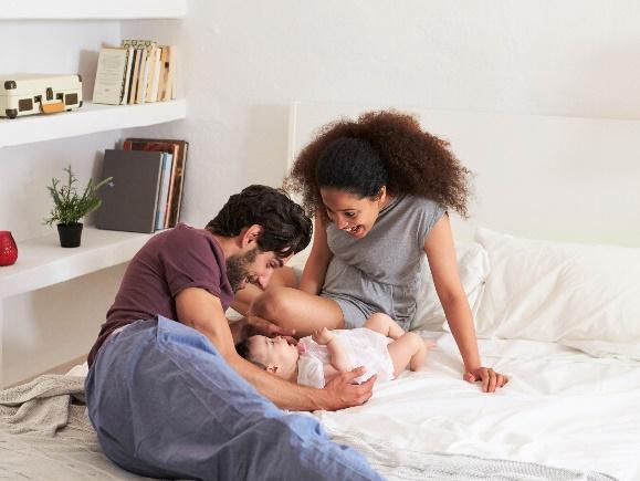Mixed Family Mom and Dad Playing With Baby On Bed