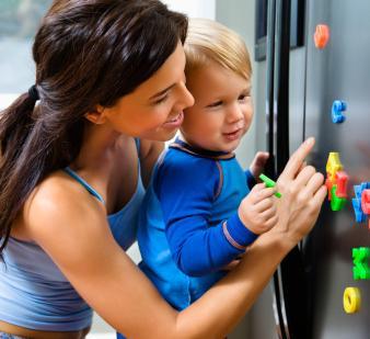 Toddler and mother with magnets on refrigerator