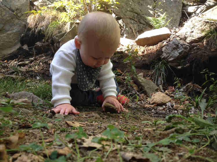 Baby playing with rock, Photo by Monica, on Instagram @mamanonthetrail