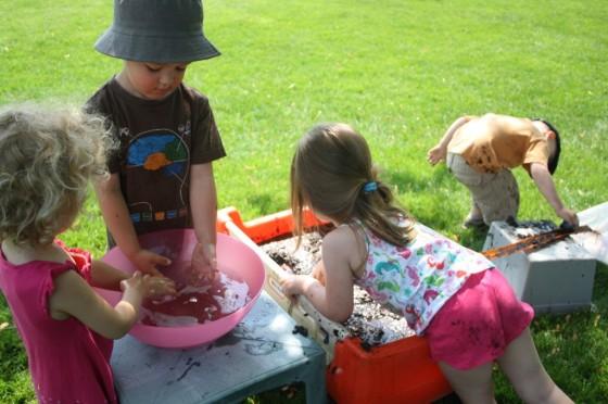 4 preschoolers playing with cars in mud