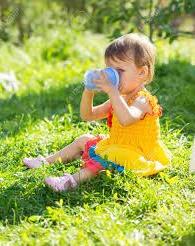 A baby sitting in the grass drinking from a blue bottle

Description automatically generated with low confidence