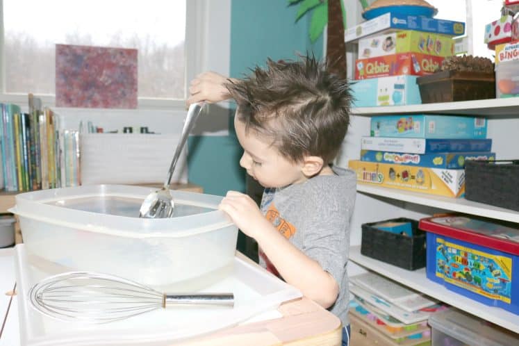 preschooler stirring water for moving water sensory bin