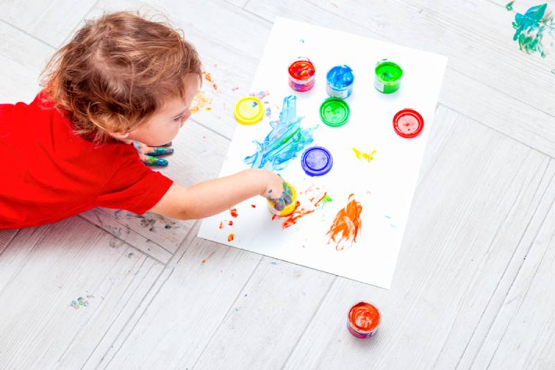 A child is playing with paints on the floor at home
