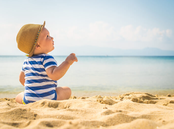 a little boy sitting on the beach