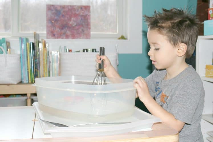 preschooler stirring moving water sensory bin