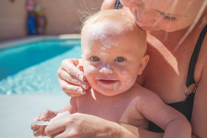 Mother putting sun screen on baby
