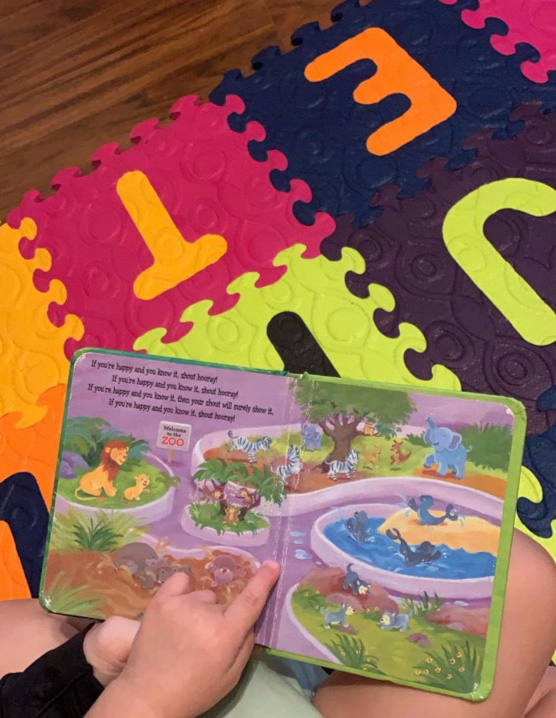 Activities for infants and toddlers reading a board book on colorful abc mat